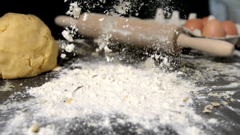 Chef-sprinkling-flour-on-black-surface