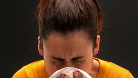 Sick-young-woman-sneezing-on-black-background