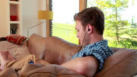 Handsome-young-man-relaxing-on-his-couch-listening-to-music