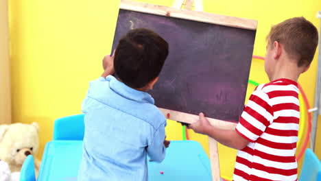 Cute-little-boys-wiping-and-knocking-over-mini-chalkboard