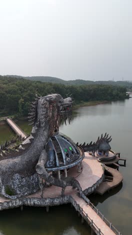 Close-rotating-aerial-around-the-abandoned-dragon-building-of-an-old-waterpark-in-Thuy-Tien-lake,-Vietnam