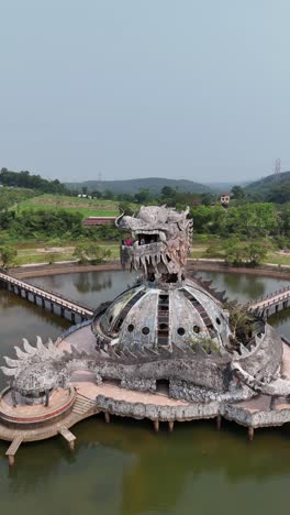 Ho-Thuy-Tien,-The-dragon-shaped-building-in-an-abandoned-water-park-In-Hue-on-Thuy-Tien-Lake,-Vietnam,-aerial-vertical-video