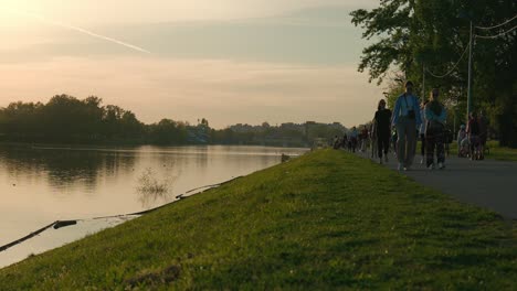 People-walking-and-biking-along-a-lakeside-path-at-sunset-in-Jarun-Lake,-Zagreb-Croatia