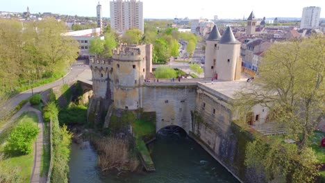 An-establishing-drone-shot-approaching-The-German-Gate,-a-medieval-bridge-castle-and-city-gate-in-the-city-of-Metz-which-is-a-popular-sightseeing-landmark-for-tourists