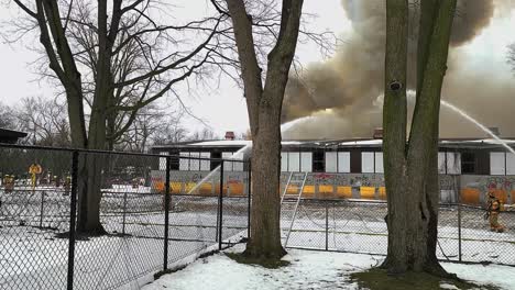 Feuerwehrleute-Löschen-Einen-Brand-In-Einem-Verlassenen-Kindergartengebäude,-Während-Eine-Schwarze-Rauchwolke-In-Die-Luft-Steigt