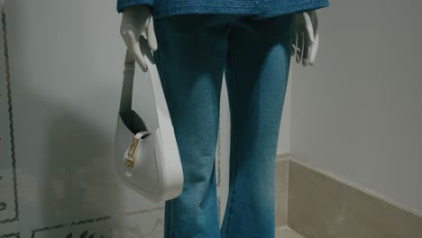 Schaufensterpuppe-Trägt-Jeans-Und-Hält-Eine-Weiße-Handtasche-In-Einem-Verkaufsdisplay