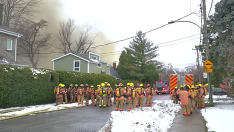 Team-of-firefighters-being-briefed-at-the-scene-of-a-building-fire-as-smoke-bellows-into-the-air-from-a-burning-abandoned-kindergarten-school