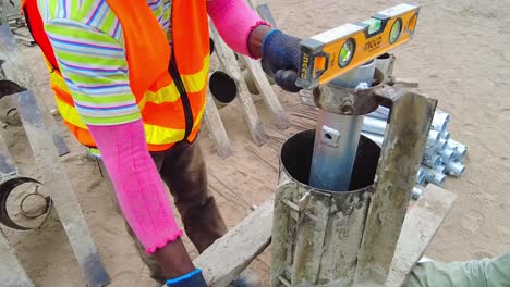 Técnico-Africano-Midiendo-Y-Ajustando-El-Molde-Del-Marco-De-Pilotes-De-Hormigón-Y-El-Soporte-Para-Pilotes-De-Hormigón-Solares-Fotovoltaicos.