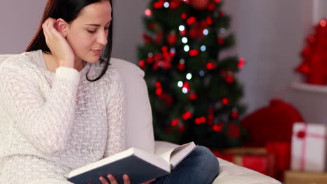 Pretty-brunette-reading-book-at-christmas-time