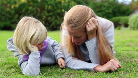 Mother-and-daughter-lying-on-grass-talking