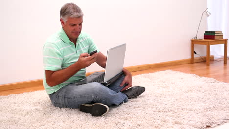 Mature-man-sitting-on-rug-using-laptop