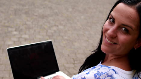 Woman-sitting-on-park-bench-using-laptop