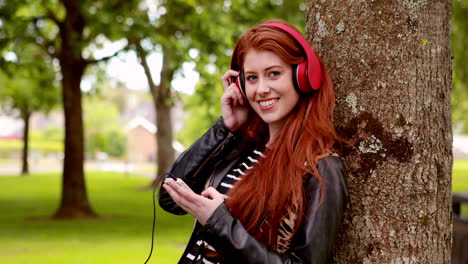 Pretty-redhead-listening-to-music-in-the-park-