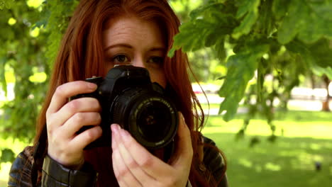 Pretty-redhead-taking-a-photo-in-the-park