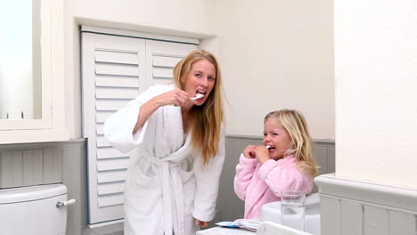Cute-little-girl-brushing-her-teeth-with-her-mother