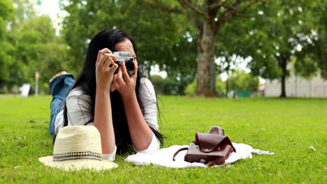 Woman-lying-on-grass-using-retro-camera