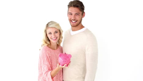 Attractive-young-couple-holding-piggy-bank
