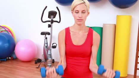 Blonde-woman-lifting-dumbbells-on-exercise-ball-
