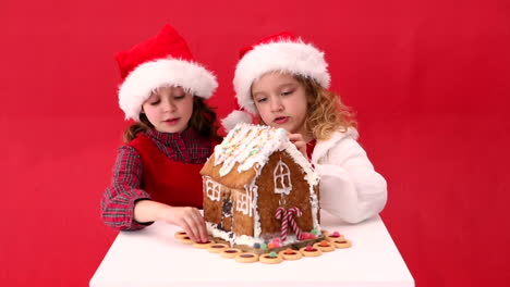 Cute-festive-sisters-making-a-ginger-bread-house