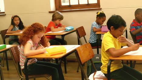 Cute-pupils-sitting-at-desk-in-classroom