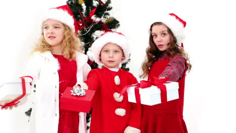Cute-siblings-offering-gifts-by-the-christmas-tree