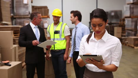 Warehouse-managers-talking-while-woman-uses-tablet-pc