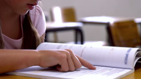 Colegiala-Leyendo-En-El-Escritorio-De-La-Escuela