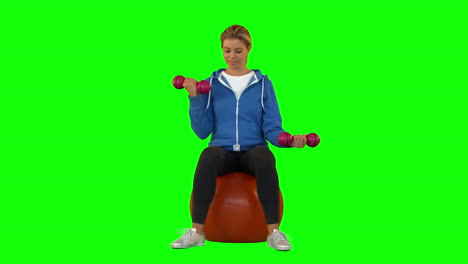 Fit-blonde-sitting-on-exercise-ball-lifting-hand-weights