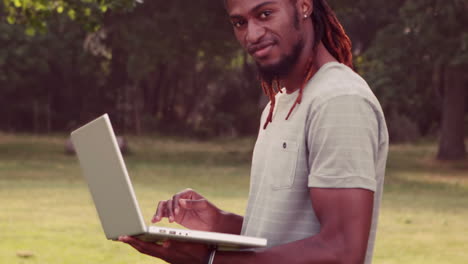 In-slow-motion-handsome-hipster-using-laptop-in-the-park
