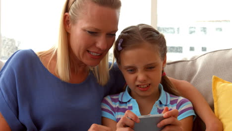 Daughter-playing-game-on-phone-with-mother