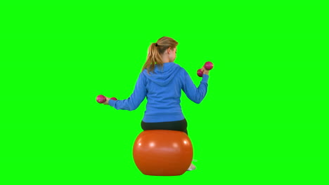 Rear-view-of-fit-woman-with-dumbbell-sitting-on-exercise-ball