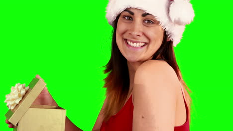 Pretty-girl-in-santa-hat-opening-a-gift-while-smiling-at-camera