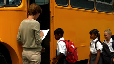 Teacher-checking-list-of-pupils-by-bus