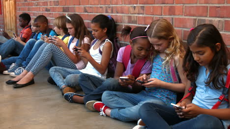 Schoolchildren-sitting-outside-using-phones