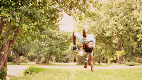 En-Cámara-Lenta,-Un-Joven-Bailarín-De-Break-Haciendo-Back-Flip-En-El-Parque.