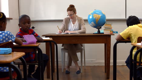 Teacher-sitting-at-top-of-classroom