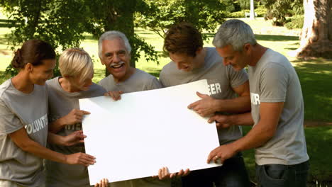 Team-of-happy-volunteers-in-the-park-showing-sign