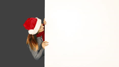 Beauty-brunette-in-santa-hat-pointing-white-poster