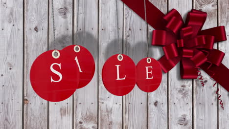 Red-sale-tags-hanging-against-wood-with-festive-bow