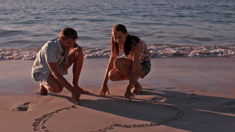 Pareja-Feliz-Dibujando-Un-Corazón-En-La-Arena