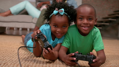 Siblings-playing-video-games-on-the-floor-while-parents-watch