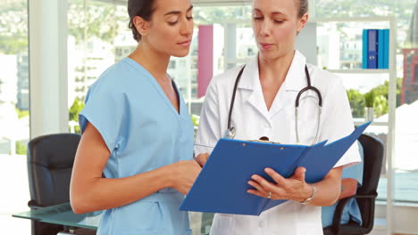 Two-doctors-looking-at-clipboard-in-medical-office