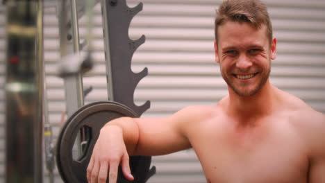 Muscular-man-putting-back-his-weights-at-crossfit-gym