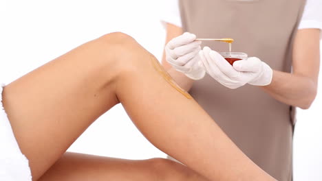 Therapist-waxing-womans-leg-at-spa-center