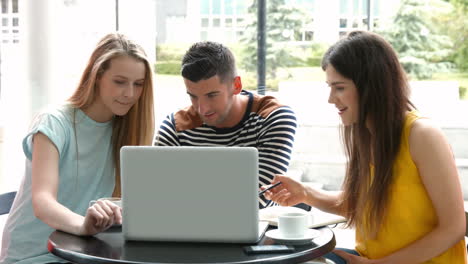 Estudiantes-Pasando-El-Rato-En-La-Cafetería-Del-Campus-Usando-Una-Computadora-Portátil