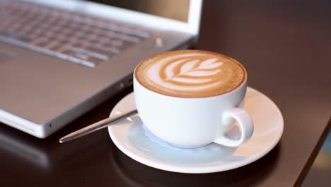 Cappuccino-Neben-Laptop-Auf-Dem-Tisch