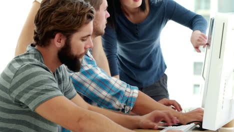 Casual-businessman-using-computer-in-front-of-discussing-colleagues