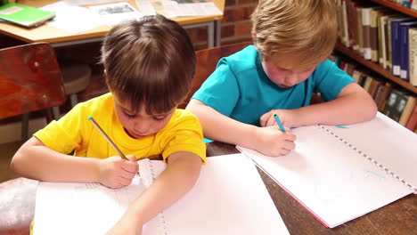 Süße-Schüler-Schreiben-In-Der-Bibliothek-