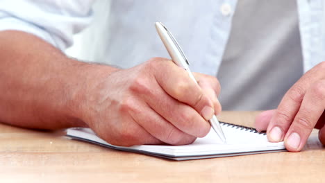 -Businessman-hands-writing-on-a-notebook