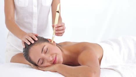 Beautiful-woman-receiving-ear-candle-treatment-at-spa-center